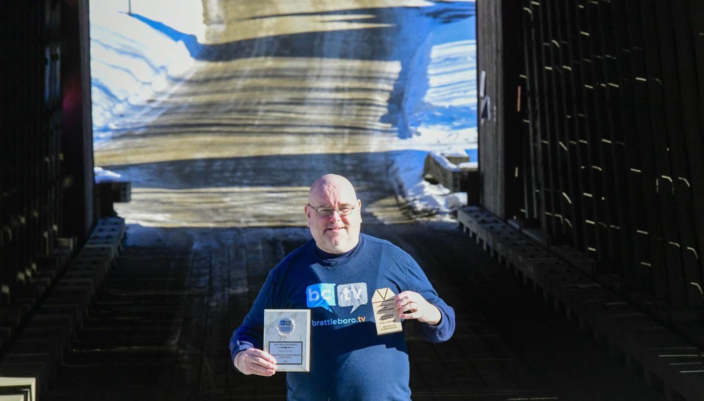 Phill Gatenby of Brattleboro holds up two awards he received while documenting the covered bridges of Vermont.